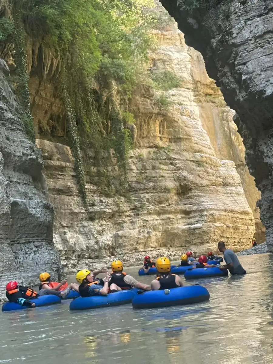 Group of tubers relaxing together beneath a massive sunlit canyon wall