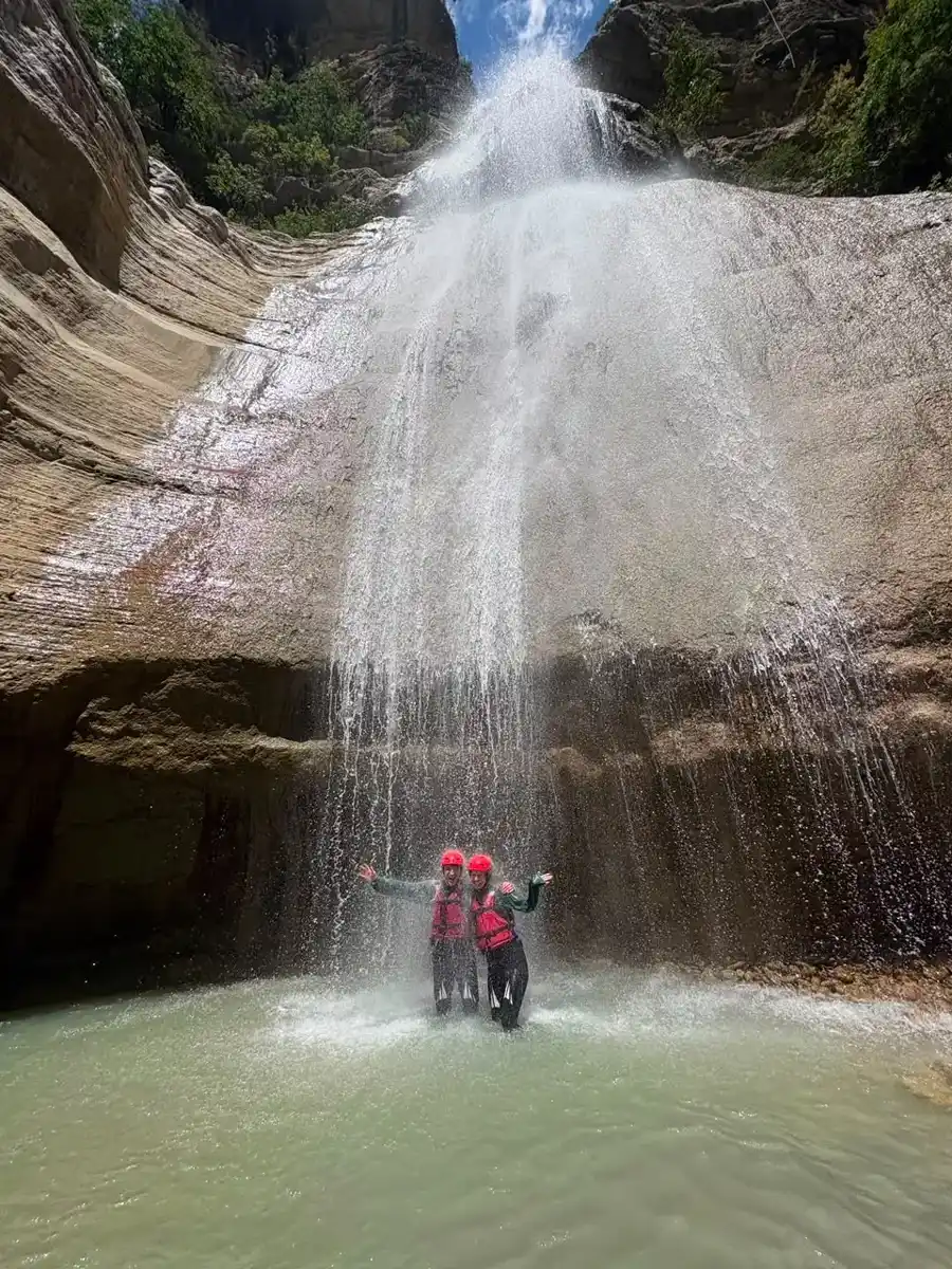 Two guests standing beneath the Waterfall of Love in Osum Canyon