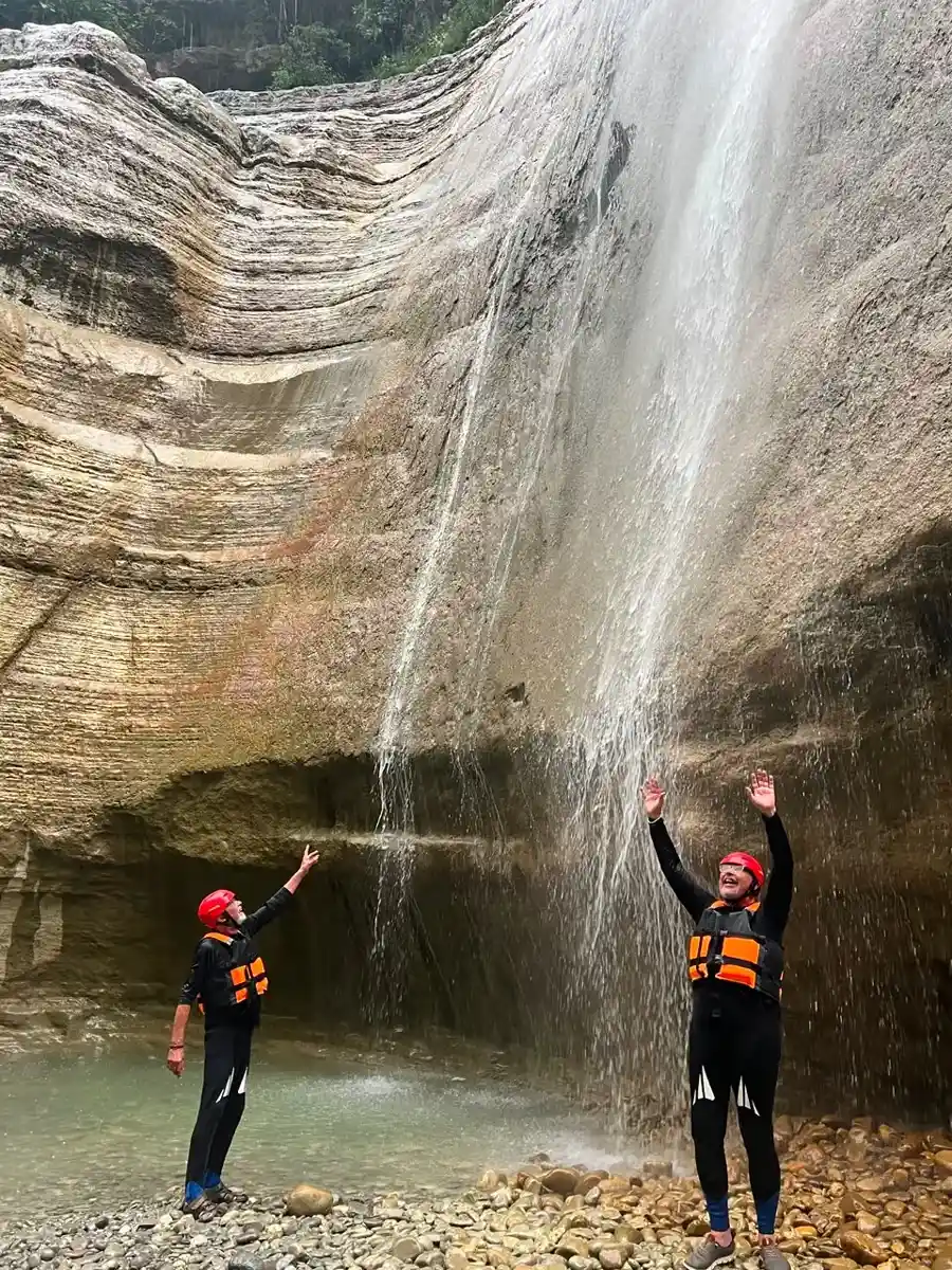 Guests reaching up into the spray of the Waterfall of Love in Osum Canyon